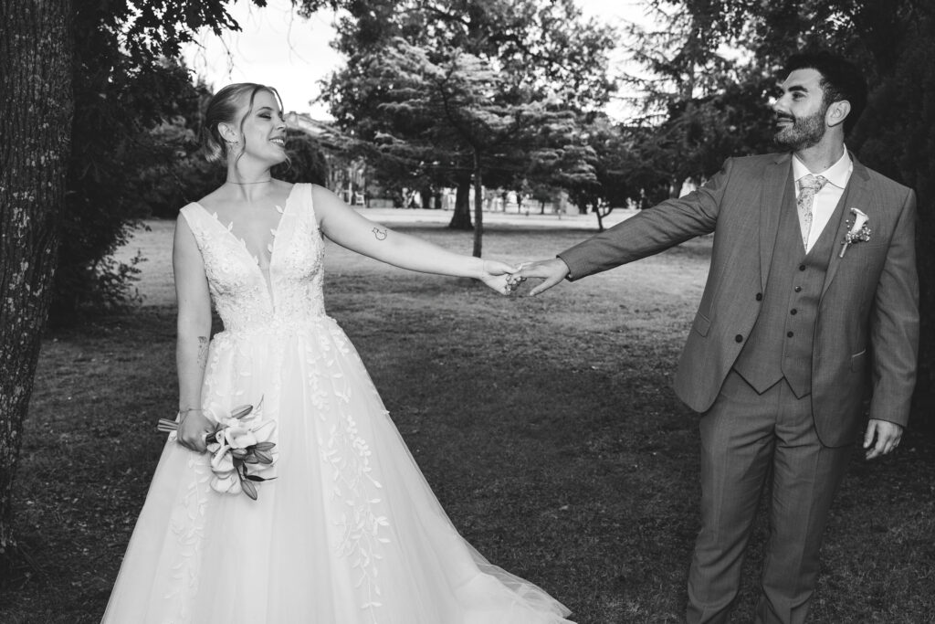 Mariés main dans la main dans un parc lors de leur séance photo de mariage en noir et blanc