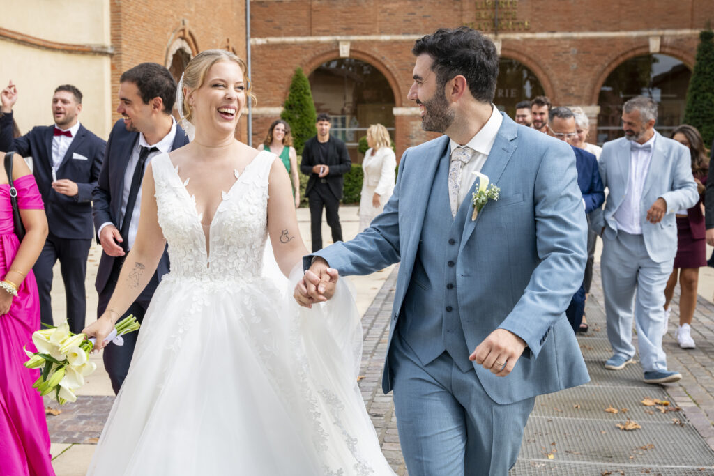 Photographie de mariage, couple marchant main dans la main, se regardant et souriant après la cérémonie.