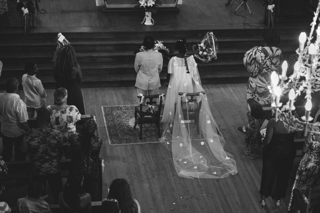Photographie de couple de mariés de dos dans l'église en noir et blanc, moment intime de la cérémonie.