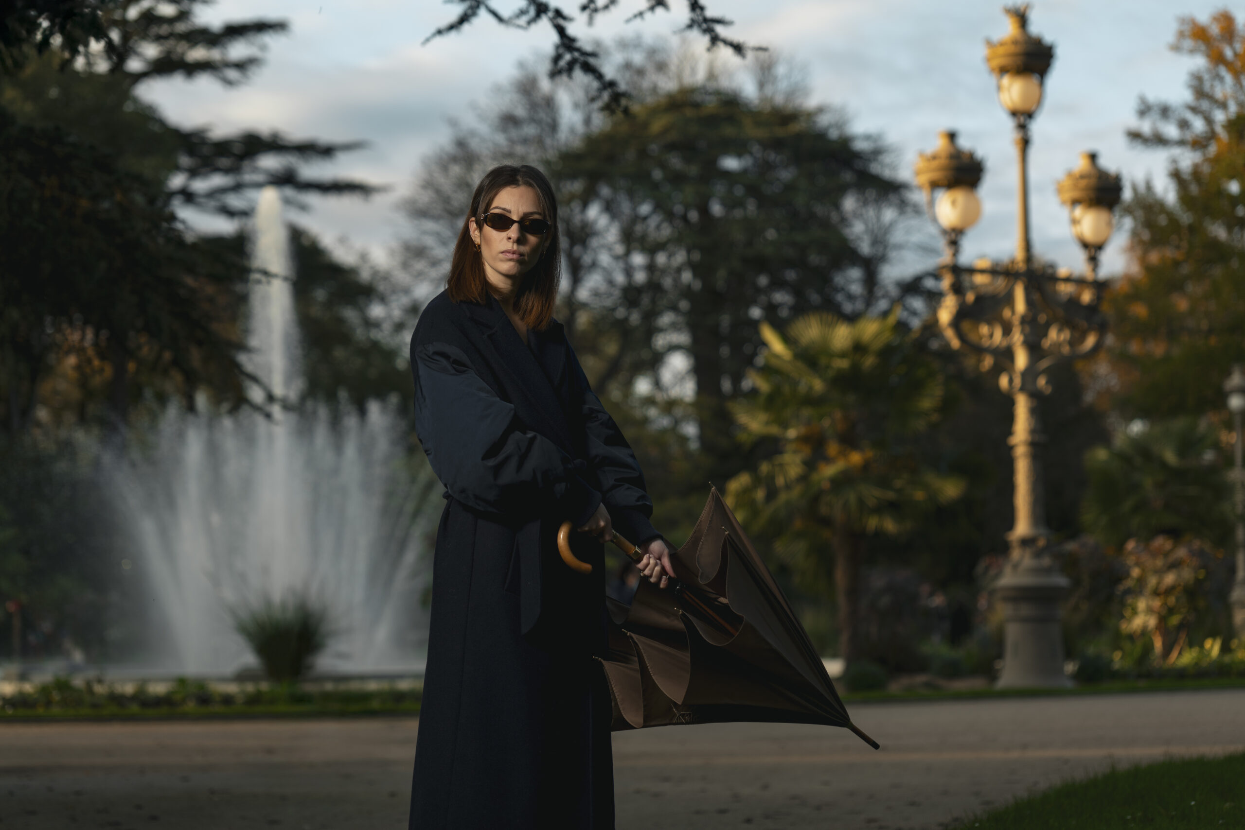 portrait professionnel style magasine d'une femme devant une fontaine avec un parapluie de Cherbourg en mains.
