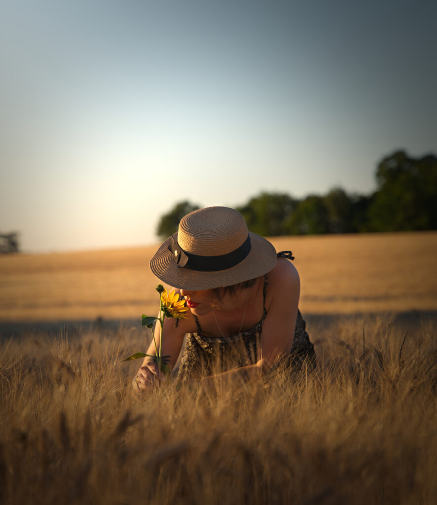 photographie d'une femme dans un champs de blé sentant un tournesol à Toulouse.