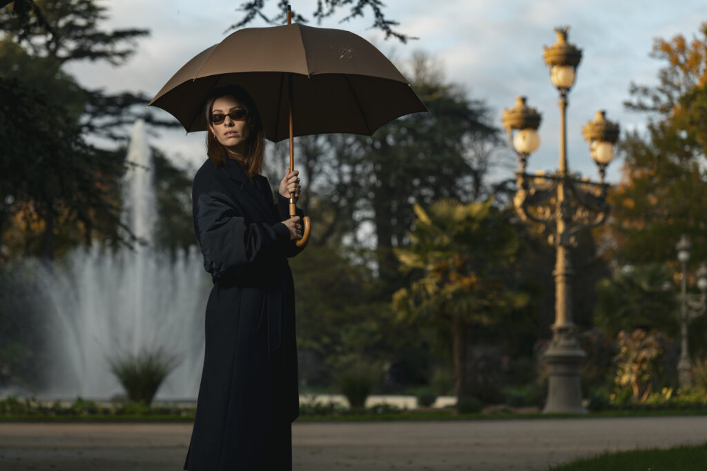 Portrait professionnel en extérieur d'une femme dans un parc à Toulouse posant de façon élégante avec un parapluie ouvert.