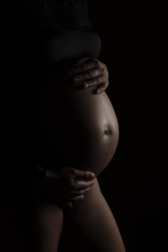 Photographie de grossesse entre ombre et lumière en studio à Toulouse