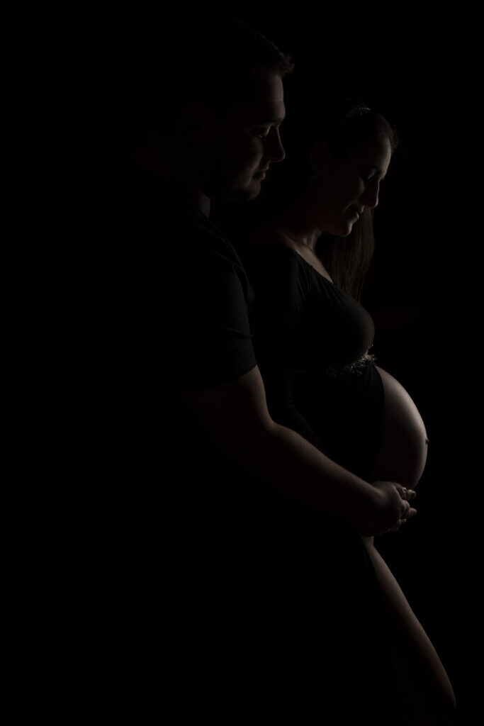 Photographie en studio à Toulouse d'une femme enceinte avec son conjoint posant pour leur séance de photographie de grossesse 